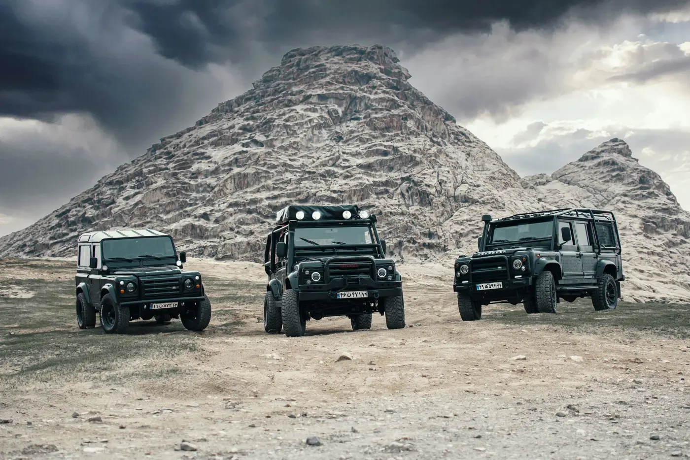 Off-road 4x4 vehicle on a dirt track below a mountain
